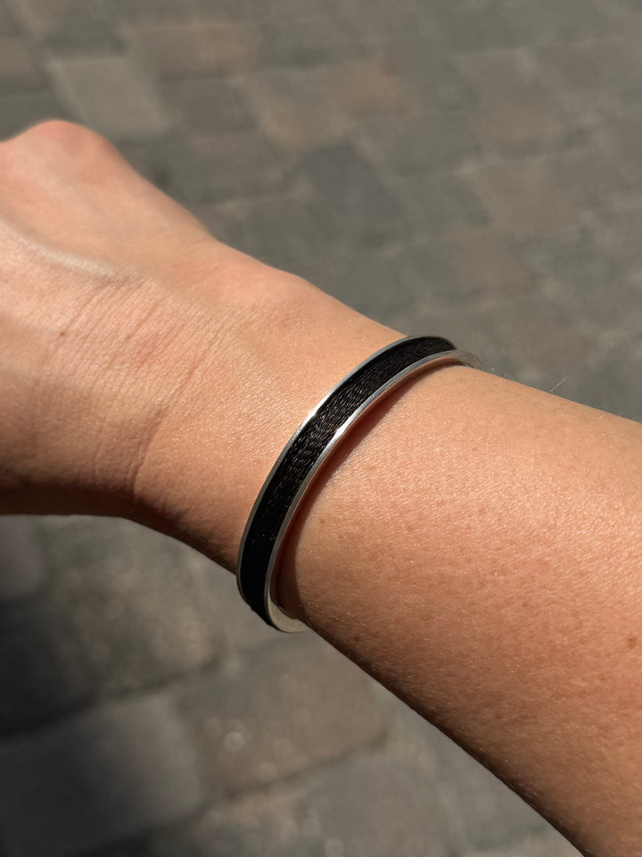 woven horsehair in sterling silver cuff bracelet sitting on wrist with a stone background
